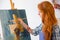 Beautiful serene young female painter painting picture in art workshop