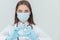 Beautiful serious female doctor in medical mask holding syringe, looking at it with eyes widely opened. Blurred needle