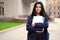 Beautiful serious smart girl brunette student holding notebooks and textbooks, stands at University on street of St. Petersburg. A