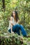 A beautiful serious teen brunette girl looking away from the camera towards the future in a wooded area in the spring