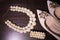 Beautiful set of women`s wedding accessories. Pearl necklace in focus, beige shoes with shiny stones on them, and a bracelet on th