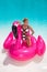 Beautiful sexy, amazing young woman in a swimming pool sitting on an inflatable pink flaming and laughing, tanned body, long hair