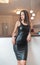 Beautiful sexy brunette young woman with black leather sexy short dress lean to a wall. Fashionable female with attractive body