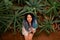 Beautiful sexy girl with multi-colored dreadlocks in a white dress lies on the ground under an orange staircase among the plants