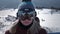 Beautiful sexy girl rider on a background of snowy mountains, looking at the camera through glasses or a mask. Hair