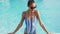 Beautiful sexy sporty girl in swimwear and sunglasses standing on pool edge by hands on blue water background