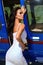 Beautiful sexy woman with dark hair in luxurious dress posing near blue helicopter