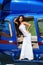 Beautiful sexy woman with dark hair in luxurious dress posing near blue helicopter