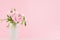 Beautiful shine soft light buttercup flowers with green leaf in delicate frosted white vase in gentle celebration pink interior.