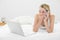 Beautiful shocked woman phoning while lying on her bed looking a