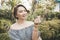 A beautiful short haired asian woman wearing an off shoulder top gives a finger heart gesture. Summer outfit