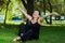 beautiful short haired woman in black clothes sitting on the green grass in the park