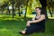 beautiful short haired woman in black clothes sitting on the green grass in the park