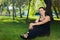 beautiful short haired woman in black clothes sitting on the green grass in the park