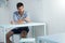 Beautiful shot of an athletic male sitting in a white furnished room with a thoughtful face