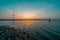 Beautiful shot of a beach with an electric windmill under a bright sunset sky