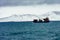 Beautiful shot of a boarded ship in blue sea full of waves in front of a snowy mountain in Iceland