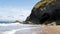 Beautiful shot of caves with greenery on the hill on a sandy shore near an ocean