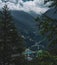 Beautiful shot of clouds on mountains of Parco Naturale Val Troncea, Italy  seen through fir trees