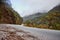 Beautiful shot of curvy asphalted road beside a hill with a mountain partially covered with clouds