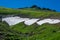 Beautiful shot of a green highlands partially covered in snow