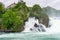 Beautiful shot of a gushing waterfall by a rocky mountain in Rhine Falls Laufen-Uhwiesen Switzerland