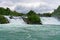 Beautiful shot of a gushing waterfall by a rocky mountain in Rhine Falls Laufen-Uhwiesen Switzerland