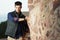 Beautiful shot of a handsome looking male posing next to a mosaic stone wall