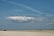 Beautiful shot of a huge isolated cloud hanging in the pure sky above the sandy shore