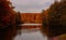 Beautiful shot of a lake in the middle of brown and green trees under a cloudy sky