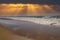 A beautiful shot of miles of vast blue ocean water and waves rolling into a beach with silky brown sand with powerful clouds