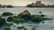 Beautiful shot of mossy rocks on a lake coast with a background of a Japanese building on a hill