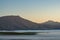 Beautiful shot of mountains and fog covering fields and trees in Overberg at a sunset