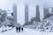 Beautiful shot of people walking in a snowy park with the Madrid four towers in the background