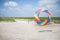 Beautiful shot of a person holding a colorful round kite in the sandy shore under the calm sky