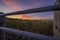 Beautiful shot of a railing near a field under a sunset sky in Grande Prairie of Alberta, Canada