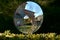 Beautiful shot of a round-shaped mirror in the park reflecting the buildings and trees in Italy