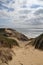 Beautiful shot of the sand dunes on the shore of the ocean under the cloudy sky in Denmark