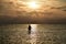 Beautiful shot of a silhouette of a paddleboarder on a lake at sunset