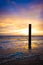 Beautiful shot of a sunset in Dutch Island of Texel beach  with beach pole and foam on the sand