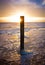 Beautiful shot of a sunset in Dutch Island of Texel beach  with beach pole and foam on the sand