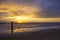 Beautiful shot of a sunset in Dutch Island of Texel beach  with beach pole and foam on the sand