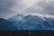 Beautiful shot of the top of the Colorado mountain range covered in snow on a cloudy gray sky