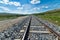 Beautiful shot of train rails moving forward to the hills under the bright calm sky