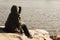 Beautiful shot of an unrecognizable woman sitting on a big rock and admiring the lake