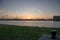 Beautiful shot of wind power plant across wide water with windmills during sunset