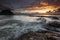 Beautiful show of water flowing movement above rock formations under cloudy scenic sky during sunset