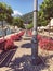 A beautiful sidewalk decorated with pink flowers near the sea surrounded by high green mountains