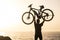 Beautiful silhouette of man holding his bike up like a winner at the beach - adult successful concept and lifestyle