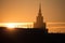 A beautiful silhouette of a tower in city during the sunrise. Morning scenery of Riga, Latvia. Tall building in city.